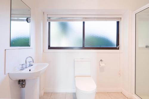 a bathroom with a sink and a toilet and a window at Ananda 3 - Bliss by the Sea in Corinella