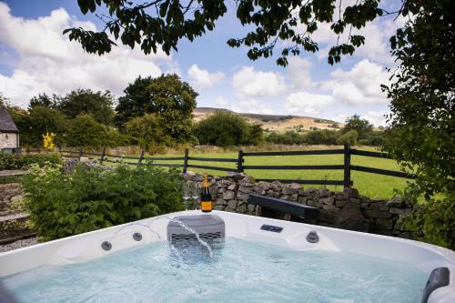 a bath tub with a bottle of wine in it at Candle House By Muse Escapes in Castleton
