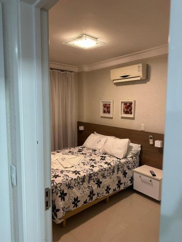 a bedroom with a bed with a white comforter at Bombinhas Summer Beach - Cond Apart Privados in Bombinhas