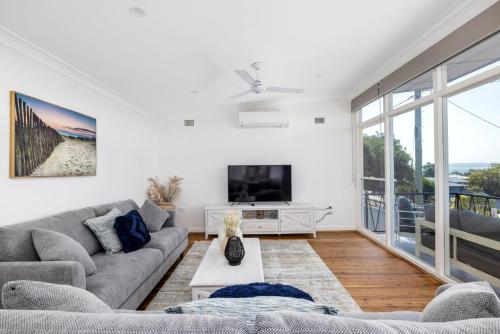 a living room with a couch and a tv at Coastal Cottage in Nelson Bay - Pet Friendly in Nelson Bay