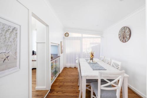 a white dining room with a white table and chairs at Coastal Cottage in Nelson Bay - Pet Friendly in Nelson Bay
