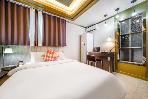 a bedroom with a bed and a desk and a window at Gongju No 25 Hotel in Gongju