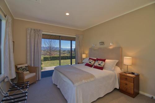ein Schlafzimmer mit einem Bett und einem großen Fenster in der Unterkunft Clayridge Cottages in Upper Moutere