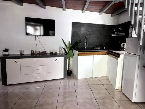 uma cozinha com armários brancos e piso em azulejo preto em Bungalow le goyavier em Goyave