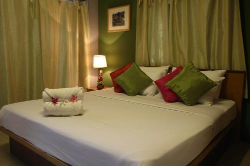 um quarto com uma grande cama branca com almofadas coloridas em Plai And Herbs Suvarnabhumi Airport em Lat Krabang