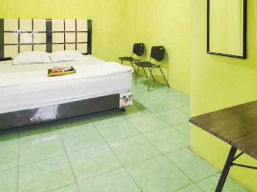 a bedroom with a bed and two chairs and a table at RedDoorz near Pelabuhan Ajibata Parapat in Parapat