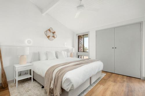 a white bedroom with a large bed and a window at Dutchies Motel Nelson Bay & Dutchmans Beach Apartments in Nelson Bay