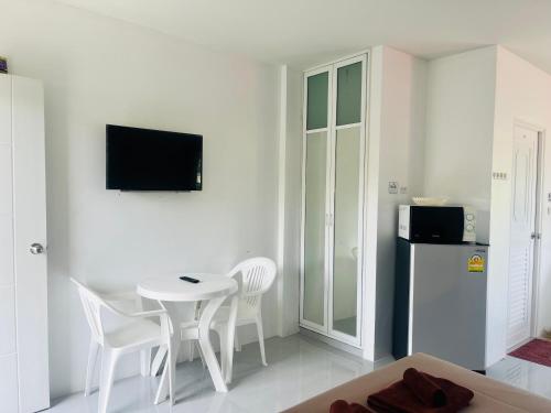 Camera bianca con tavolo, sedie e frigorifero. di Rest Mind House a Ban Lum Fuang