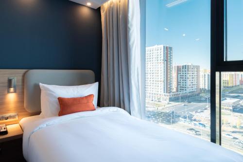 a bed in a hotel room with a large window at Holiday Inn Express - Astana - Turan by IHG in Astana