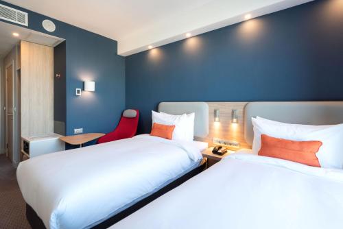 a hotel room with two beds and a red chair at Holiday Inn Express - Astana - Turan by IHG in Astana