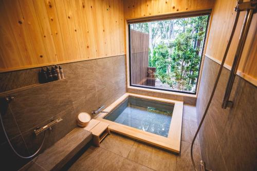 Baño con bañera en la esquina de una habitación en SAUNA FOREST CABIN Karuizawa Miyota - Vacation STAY 23219v en Oiwake