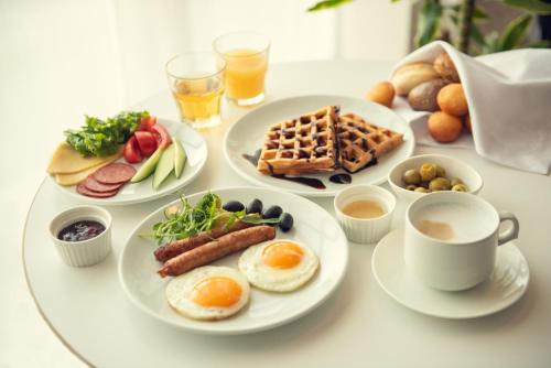 a table with plates of breakfast foods and a cup of coffee at Holiday Inn Express - Astana - Turan by IHG in Astana