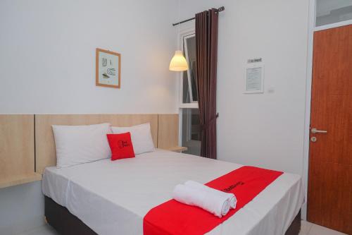 Un dormitorio con una cama con almohadas rojas y blancas. en RedDoorz Syariah @ Tlogosari Semarang, en Alastuwo