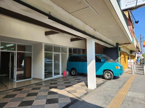 een blauw busje geparkeerd voor een gebouw bij Homestay Titiknol Yogya in Yogyakarta