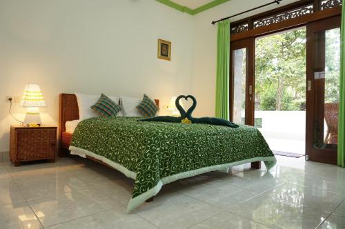 a bedroom with a green bed with a swan on it at Argasoka Bungalows in Ubud