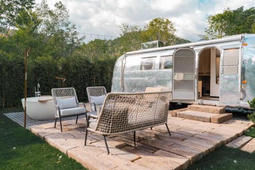 an rv with chairs and a tub in a yard at Hotel Labaris Khao Yai in Mu Si