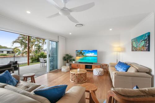 a living room with two couches and a tv at Lake House On Magellan 58 Ramsay Crescent in Golden Beach