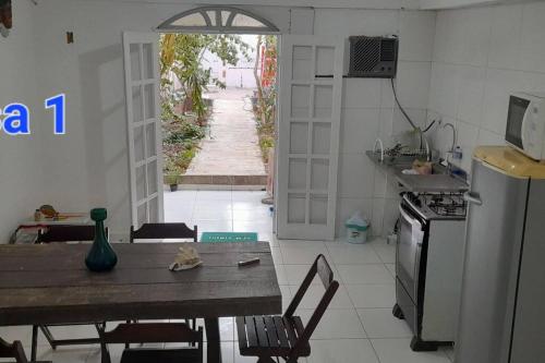 eine Küche mit einem Tisch, einem Herd, einem Tisch und Stühlen in der Unterkunft Areia Branca Casas / casa 1. in Cabo Frio