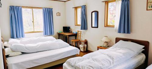 two beds in a room with blue curtains at Stardew in Otari