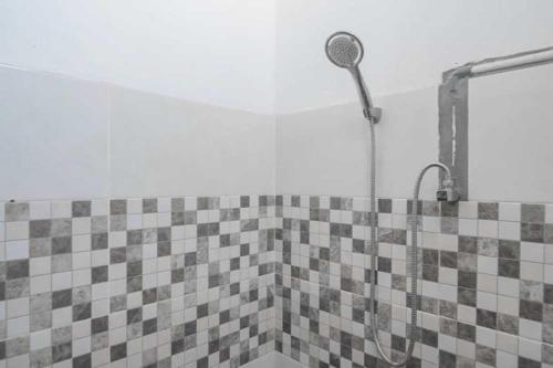 a shower in a bathroom with a tiled wall at OYO 93306 Rinjani Guest House in Balikpapan