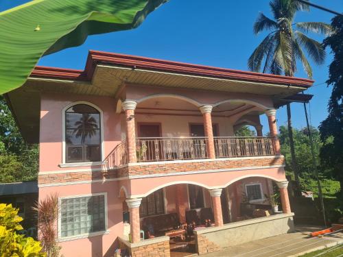 a large pink house with a balcony at Rotunda Inn home stay in Pagadian