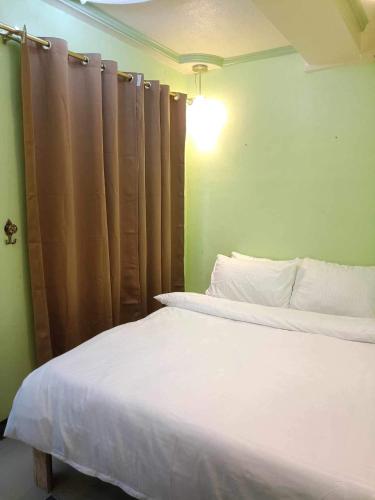 Casa De Familia Staycation في مانيلا: غرفة نوم بسرير ابيض وجدار اخضر