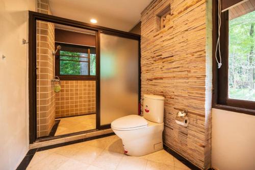 La salle de bains est pourvue de toilettes et d'un mur en briques. dans l'établissement Khao Yai Log House, à Pak Chong