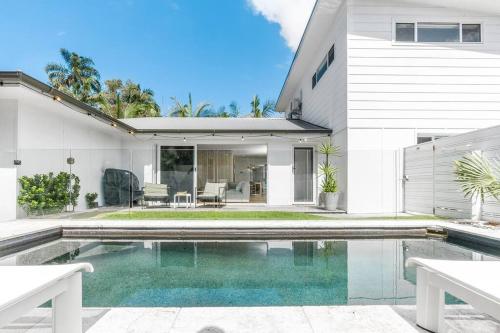 a white house with a swimming pool in front of it at Pool House - Peaceful Luxury, Byron Bay in Byron Bay