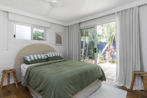a bedroom with a bed and a large window at The Pool House - Byron Bay in Byron Bay