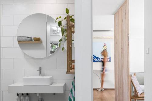 a bathroom with a sink and a mirror and a woman in the background at Pool House - Peaceful Luxury, Byron Bay in Byron Bay