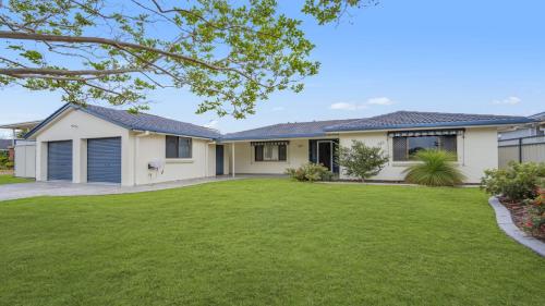 uma casa com um relvado verde em frente em Hooked On Hibbard em Port Macquarie