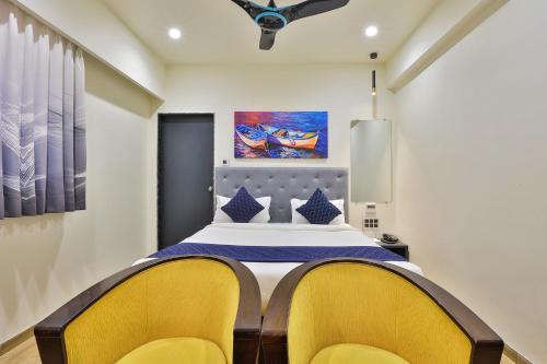 a bedroom with a bed with two yellow chairs at FabHotel Prime Empyrean in Gandhinagar