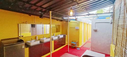 a bathroom with three sinks and a yellow wall at xplorest in Mysore