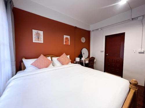 a bedroom with a large white bed with orange walls at SO One Silom Apartment in Bang Rak