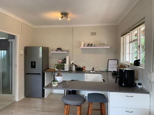 a kitchen with a counter and a refrigerator and chairs at Private & Spacious Olive cottage in Bloubergstrand in Cape Town