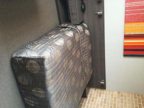 a metal bed in the corner of a room at Alexander The Great Motel in Windsor