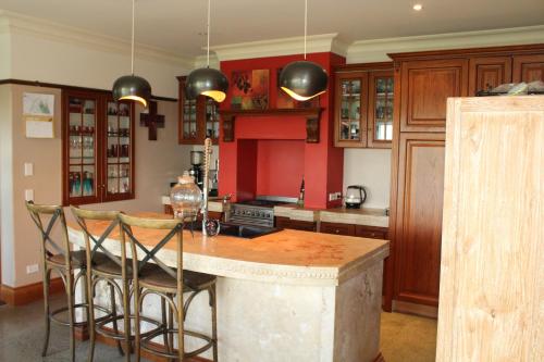 cocina con paredes rojas y mesa con sillas en Hadlow Sunrise Retreat, en Timaru