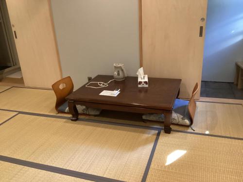 einen Holztisch und Stühle in einem Zimmer in der Unterkunft Sana Inn Town in Wakayama