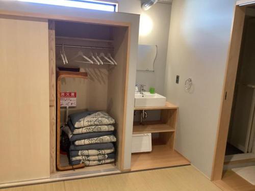 a bathroom with a sink and a closet with towels at Sana Inn Town in Wakayama