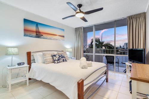 a bedroom with a bed with a ceiling fan and a balcony at Amazing Water Views Surfers Paradise in Gold Coast