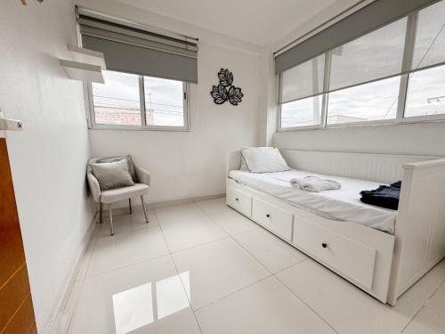 a white bedroom with a bed and a chair at Beautiful Apartment, Airport, Downtown, Foro Sol in Mexico City