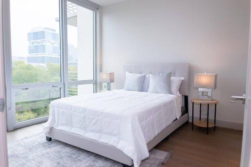 Luxurious & cozy 2bedroom/2bath apt downtwn Dallas في دالاس: غرفة نوم بيضاء مع سرير كبير ونافذة كبيرة