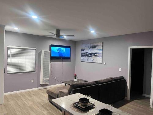 a living room with a couch and a tv on the wall at A beautiful guest house/ Downey in Downey