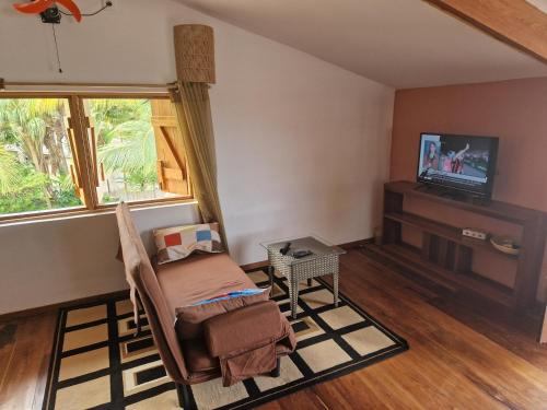 ein Wohnzimmer mit einem Stuhl und einem TV in der Unterkunft L'Ylang Ylang Auberge d'AMBATOLOAKA in Ambatoloaka