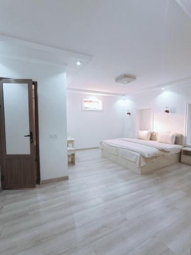 a white bedroom with a large bed and a wooden floor at Dari Zanjir in Samarkand