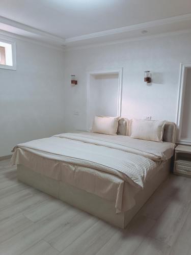 a white bedroom with a large bed with white sheets and pillows at Dari Zanjir in Samarkand