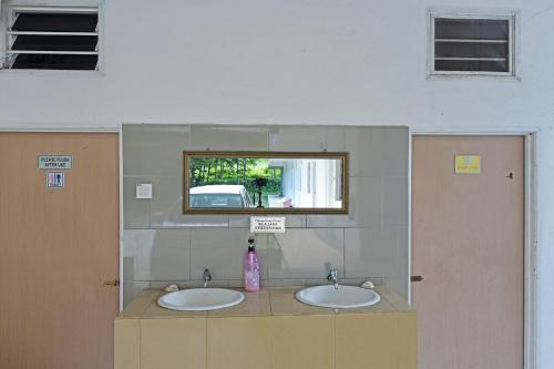 a bathroom with two sinks and a mirror at OYO 90879 Eleven Inn in Kuah