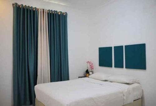 sypialnia z 2 łóżkami i zielonymi zasłonami w obiekcie OYO 93311 Pesona Orange Homestay w mieście Padang