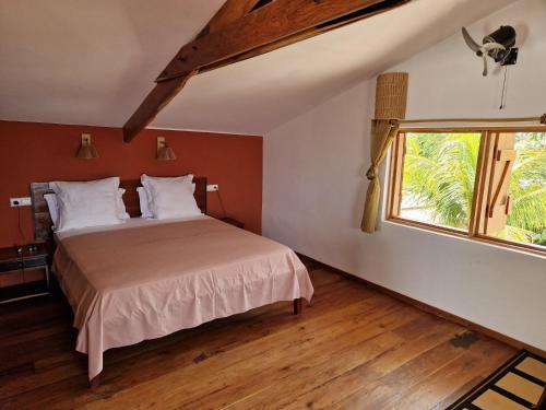 1 dormitorio con cama y ventana en L'Ylang Ylang Auberge d'AMBATOLOAKA, en Ambatoloaka