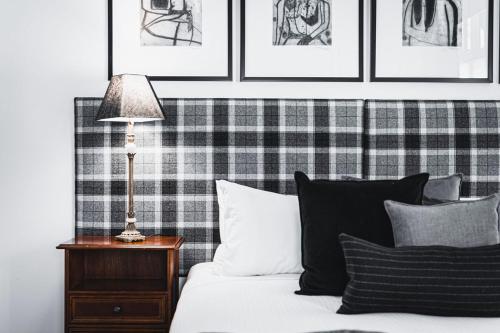 a bed with black and white pillows and a lamp at Hotel Bellinzona Daylesford in Hepburn Springs